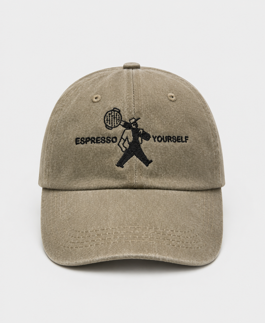 Beige cap with black embroidered design and text on a white background